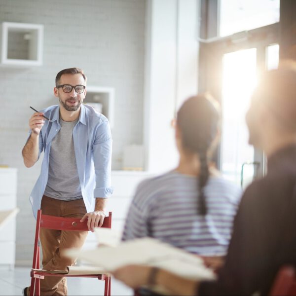 Young professional painting teacher standing in front of audience and explaining his students main rules