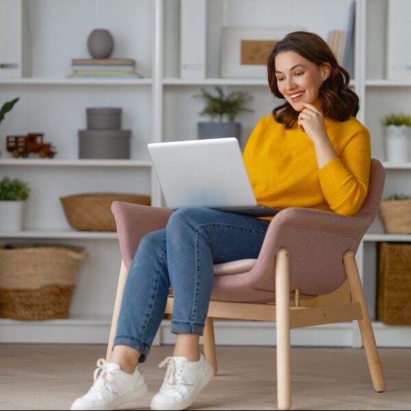 Happy casual beautiful woman using laptop at home.