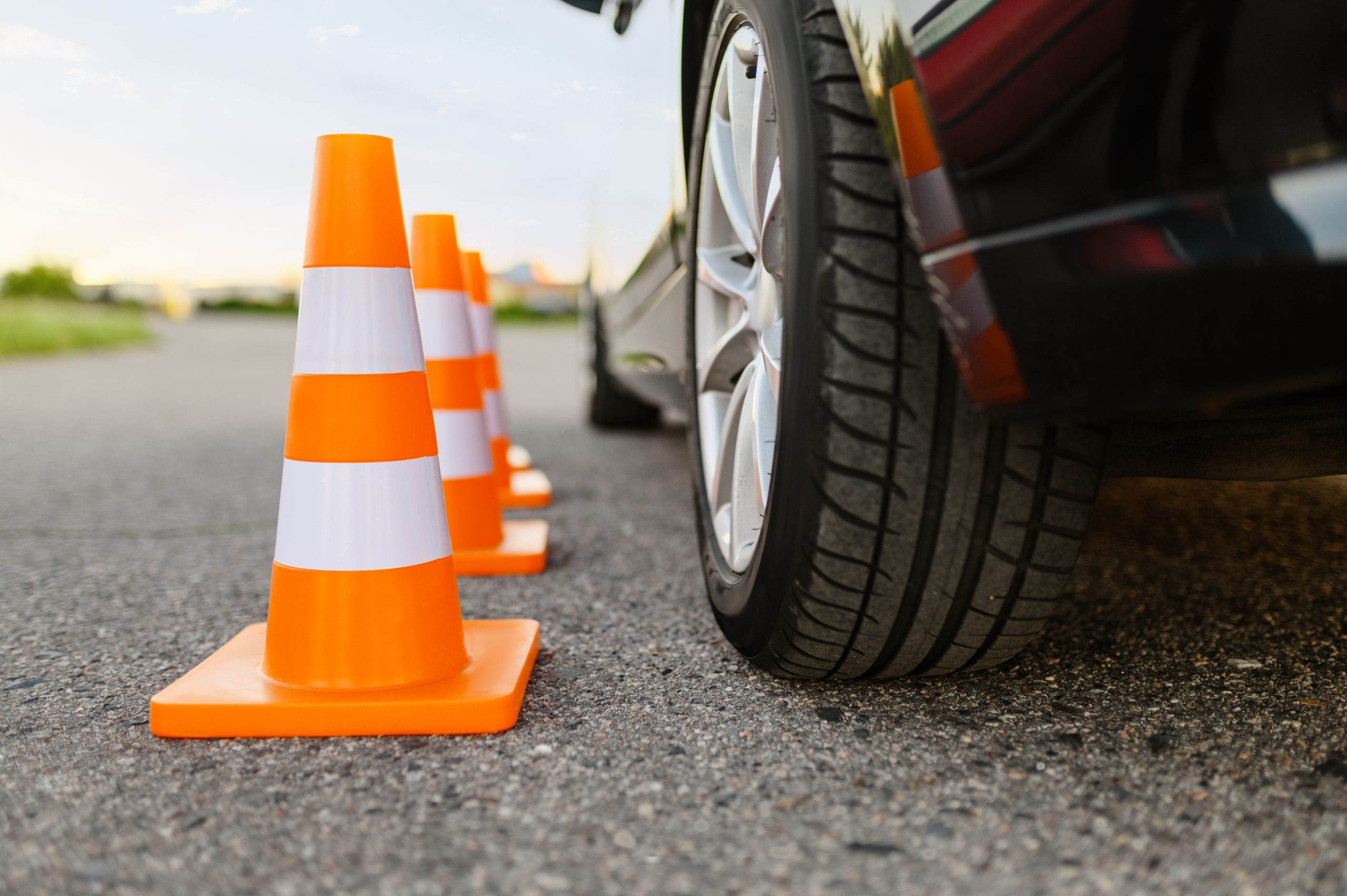 Car and orange traffic cones, lesson in driving school concept, nobody. Teaching to drive vehicle theme. Driver's license education