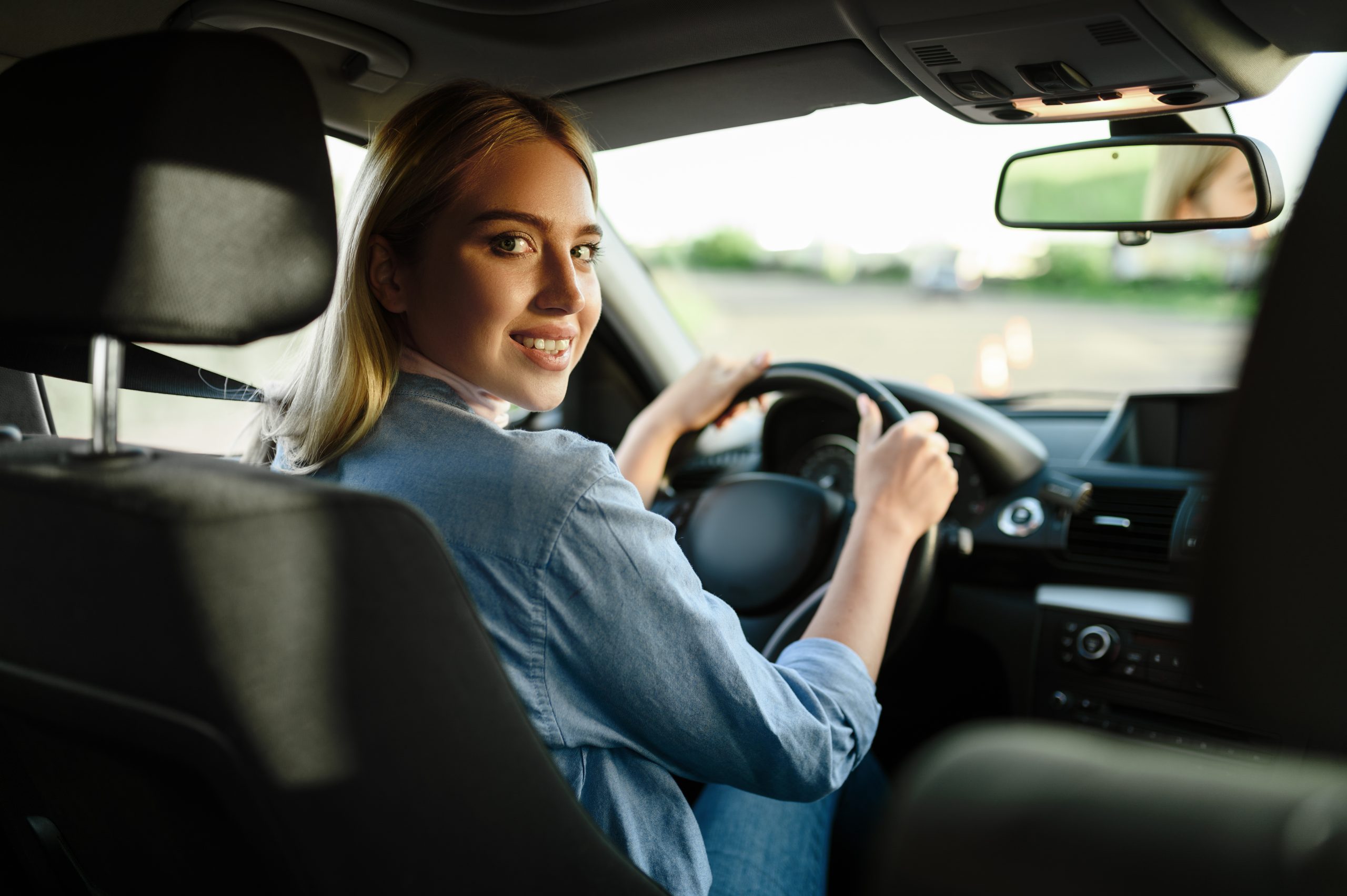 Smiling female student in the car, lesson in driving school. Man teaching lady to drive vehicle. Driver's license education